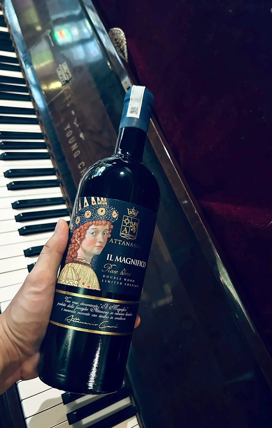Una bottiglia di Il Magnifico tenuta in mano accanto a un pianoforte